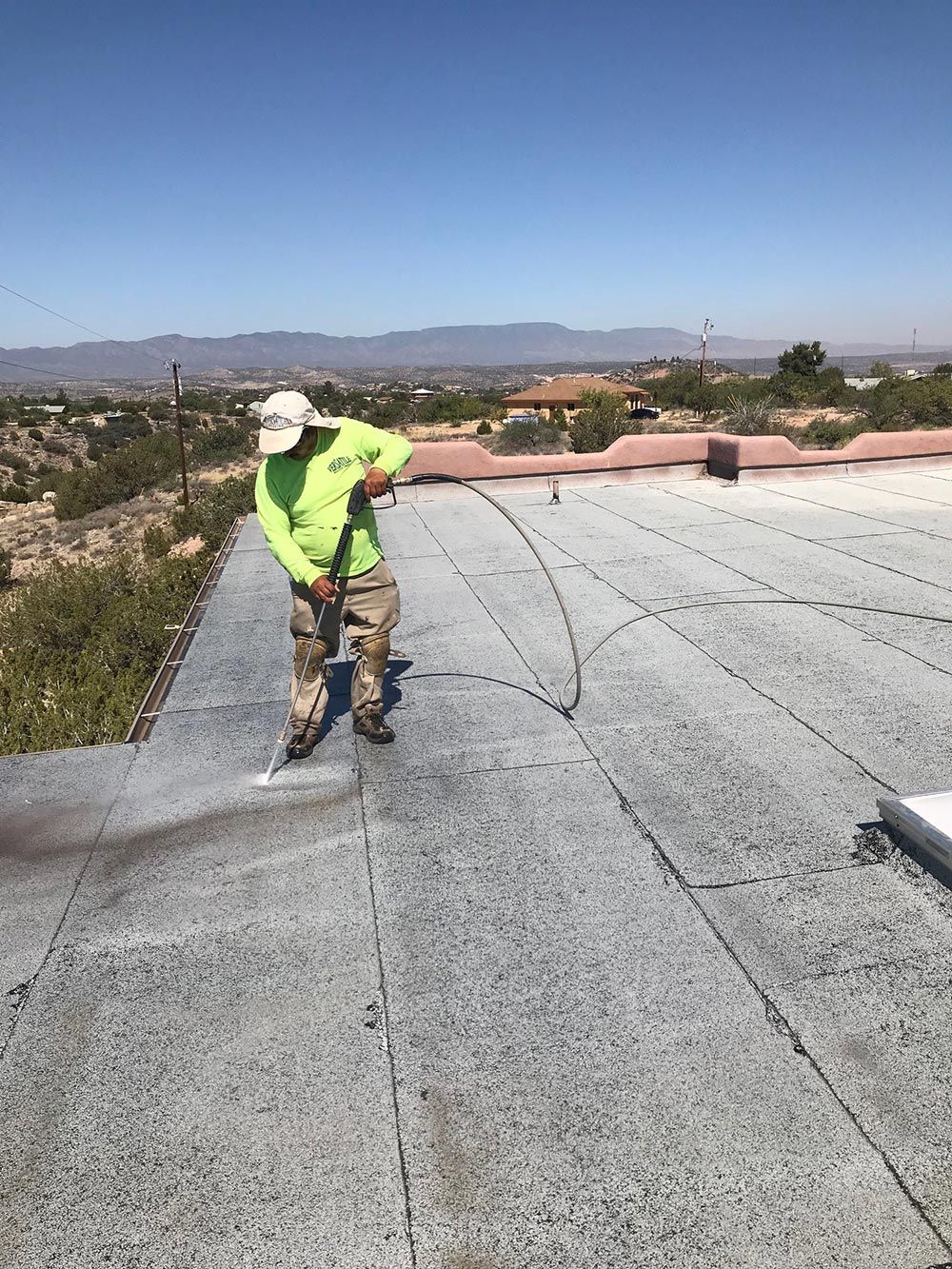 A man is spraying a roof with a hose.