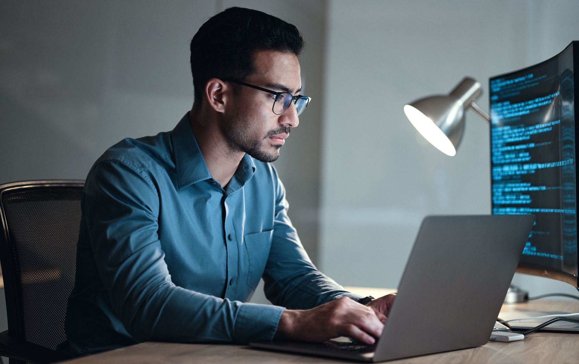 A man is sitting at a desk using a laptop computer updating software.