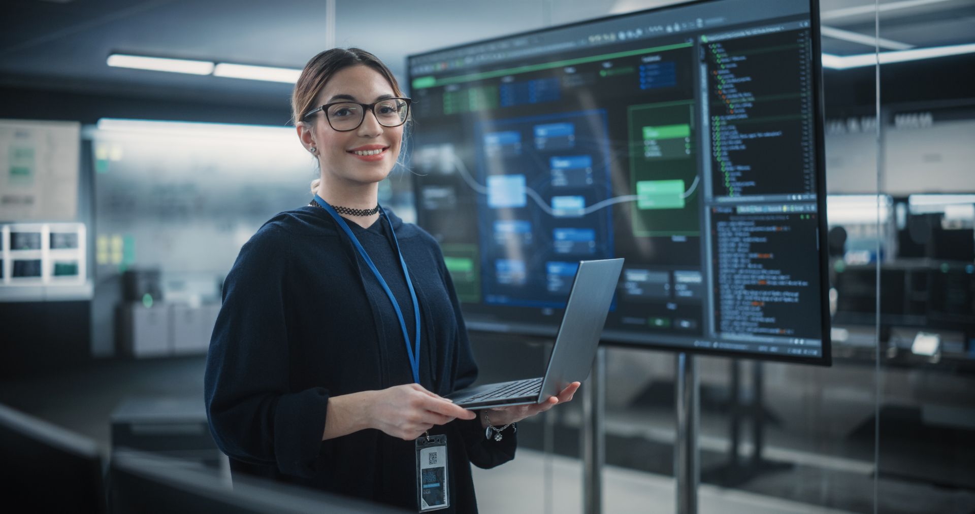 a woman is holding a laptop in front of a large screen implementing cloud computing services