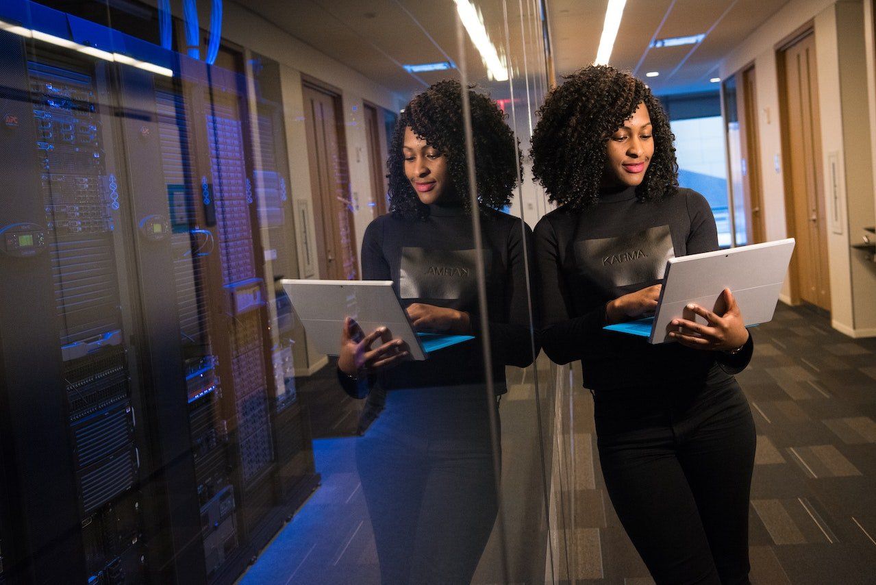 a woman is standing in a hallway holding a tablet computer in front of IT infrustructure