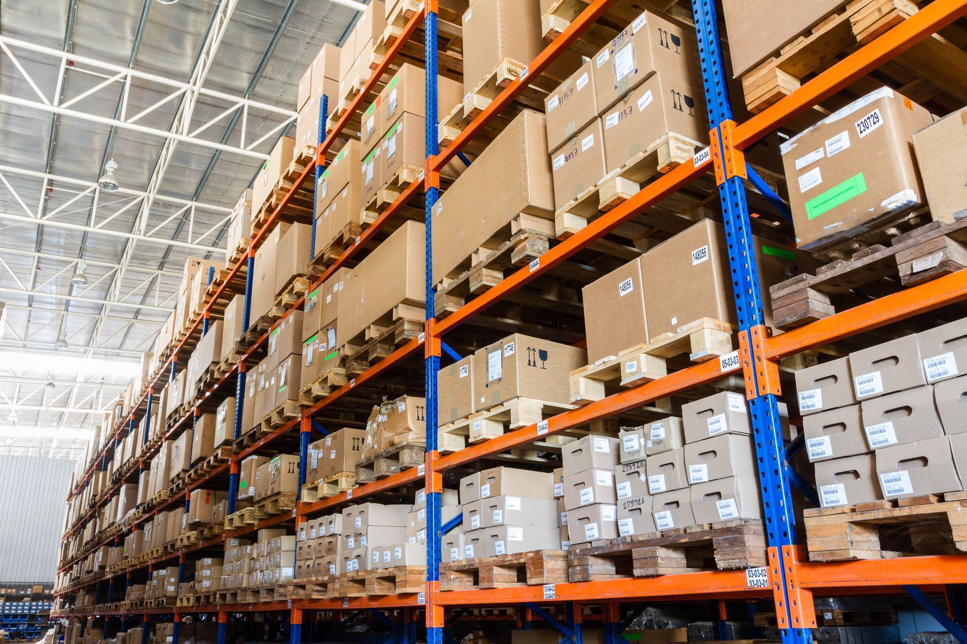 Warehouse shelves stacked with cardboard boxes. Orange and blue shelving.