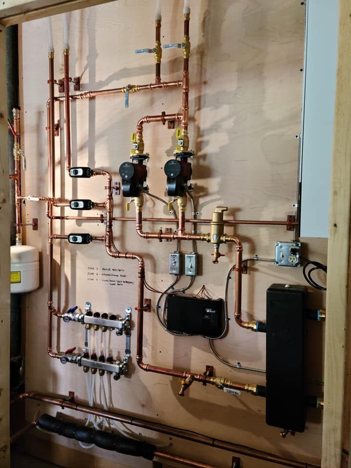 Copper pipes and heating components mounted on a wooden board.