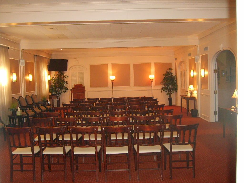Rows of chairs face a podium in a warm-lit room, possibly for a service or event.