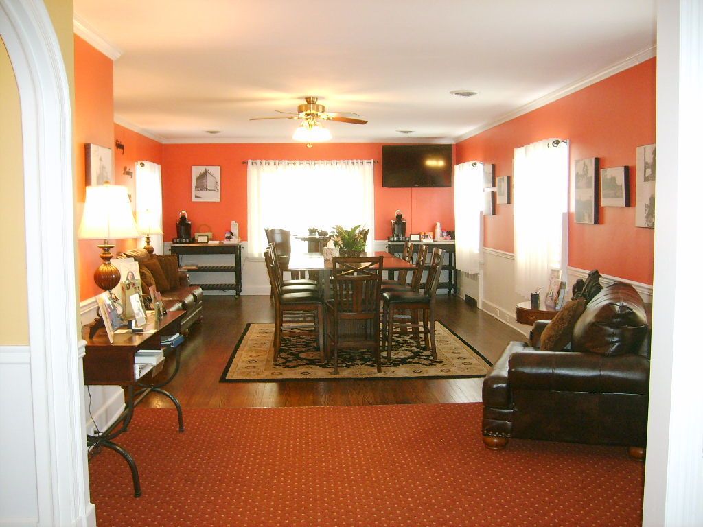 Spacious room with coral walls, dark wood furniture, and a large dining table.