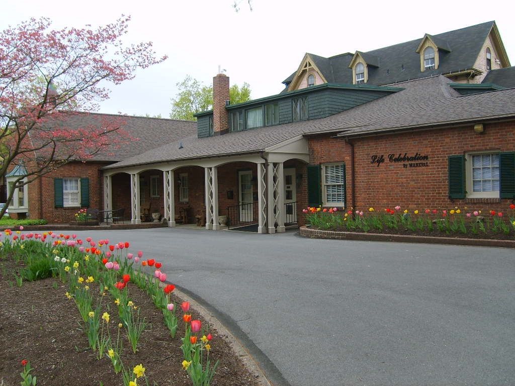 Brick building with covered porch, tulips in front, and curved driveway.