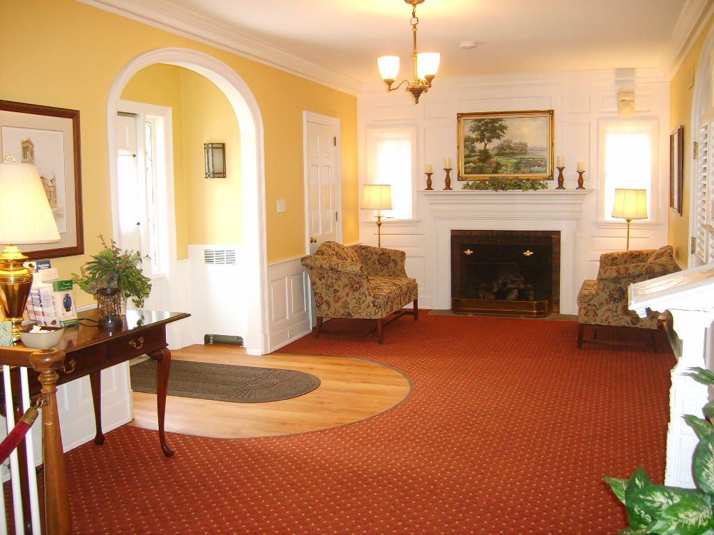 Cozy lobby with fireplace, seating, and a round wooden floor detail in a room with yellow walls.