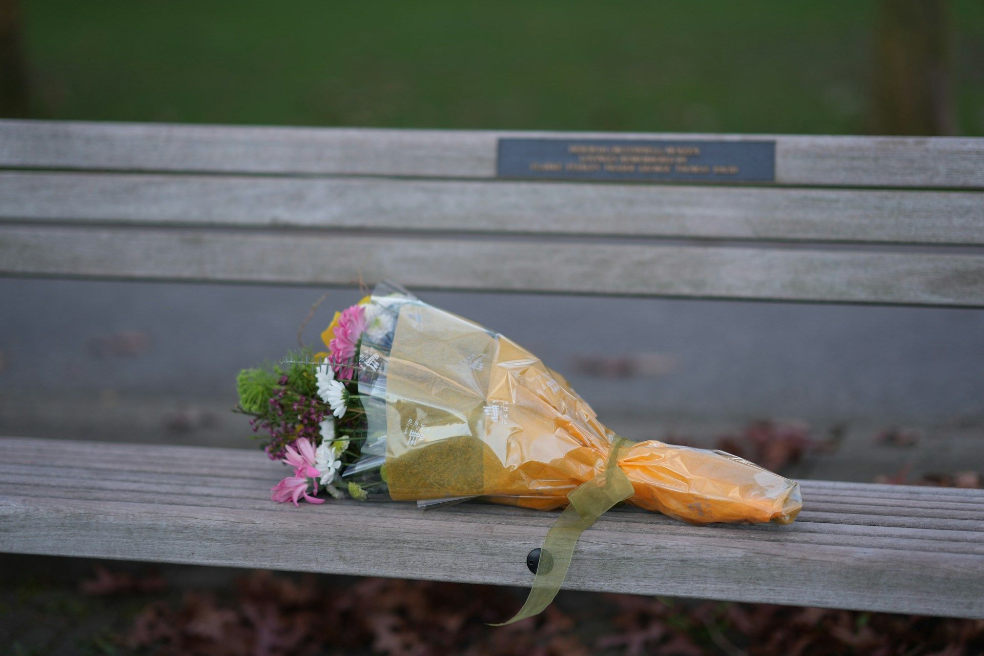 Bouquet of flowers resting on a park bench as a touching public memorial and tribute to a loved one.