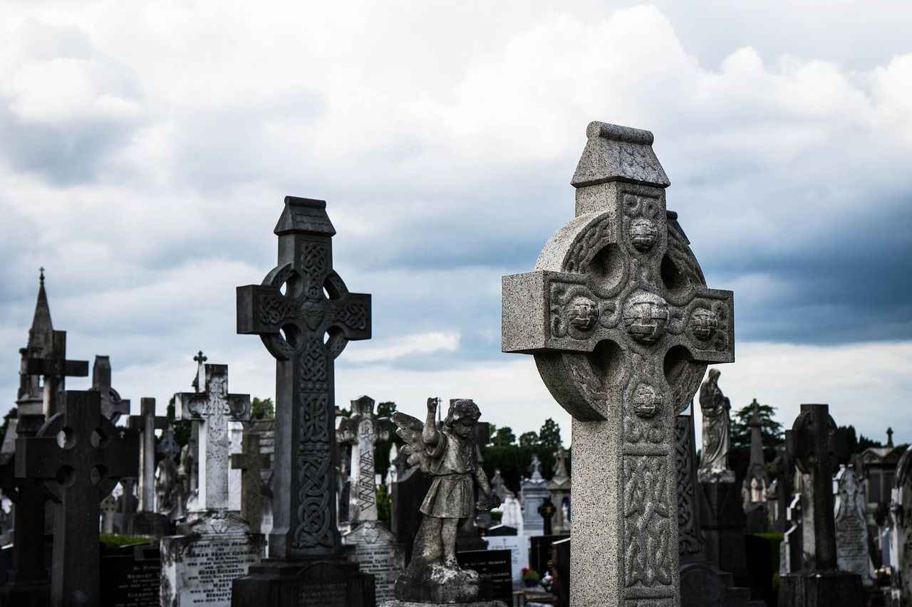 Gravestones at Glasnevin Cemetery in Dublin, Ireland, with trees and historic setting