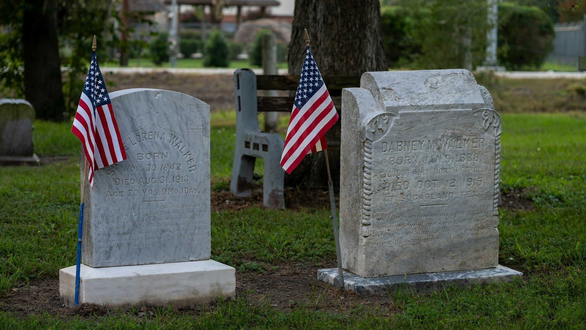 Two veteran headstones with American flags placed in front, honoring their service and memory on Memorial Day.