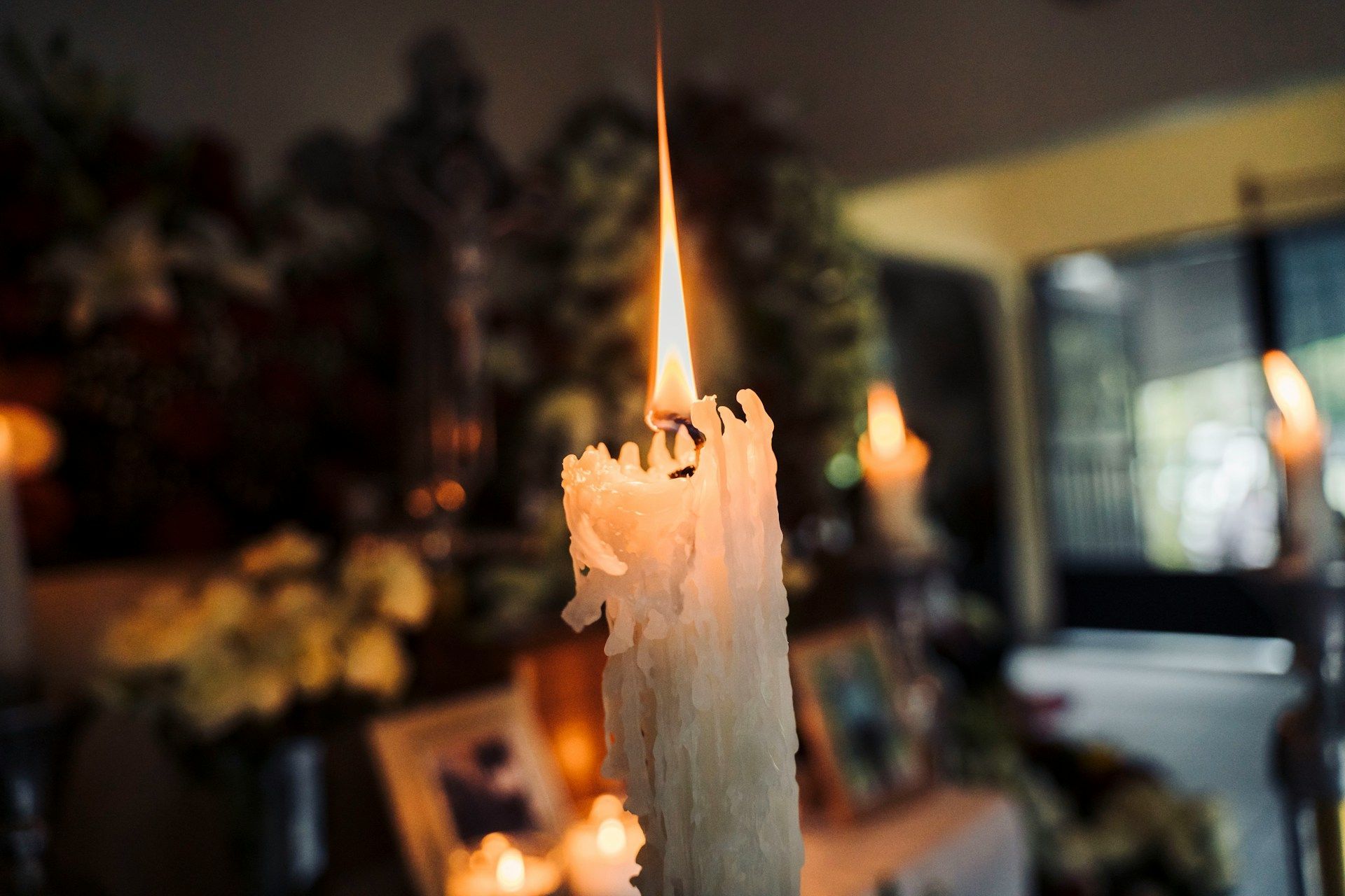 Peaceful white candle burning softly in a calm, dimly lit room creating a serene atmosphere.