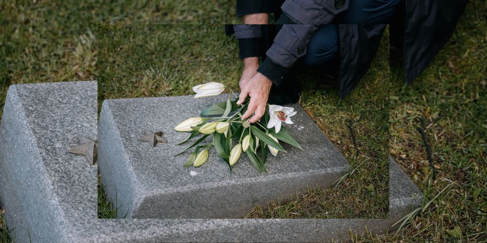 Hand gently placing white lilies on a gravestone marked with a military star, honoring a fallen serv