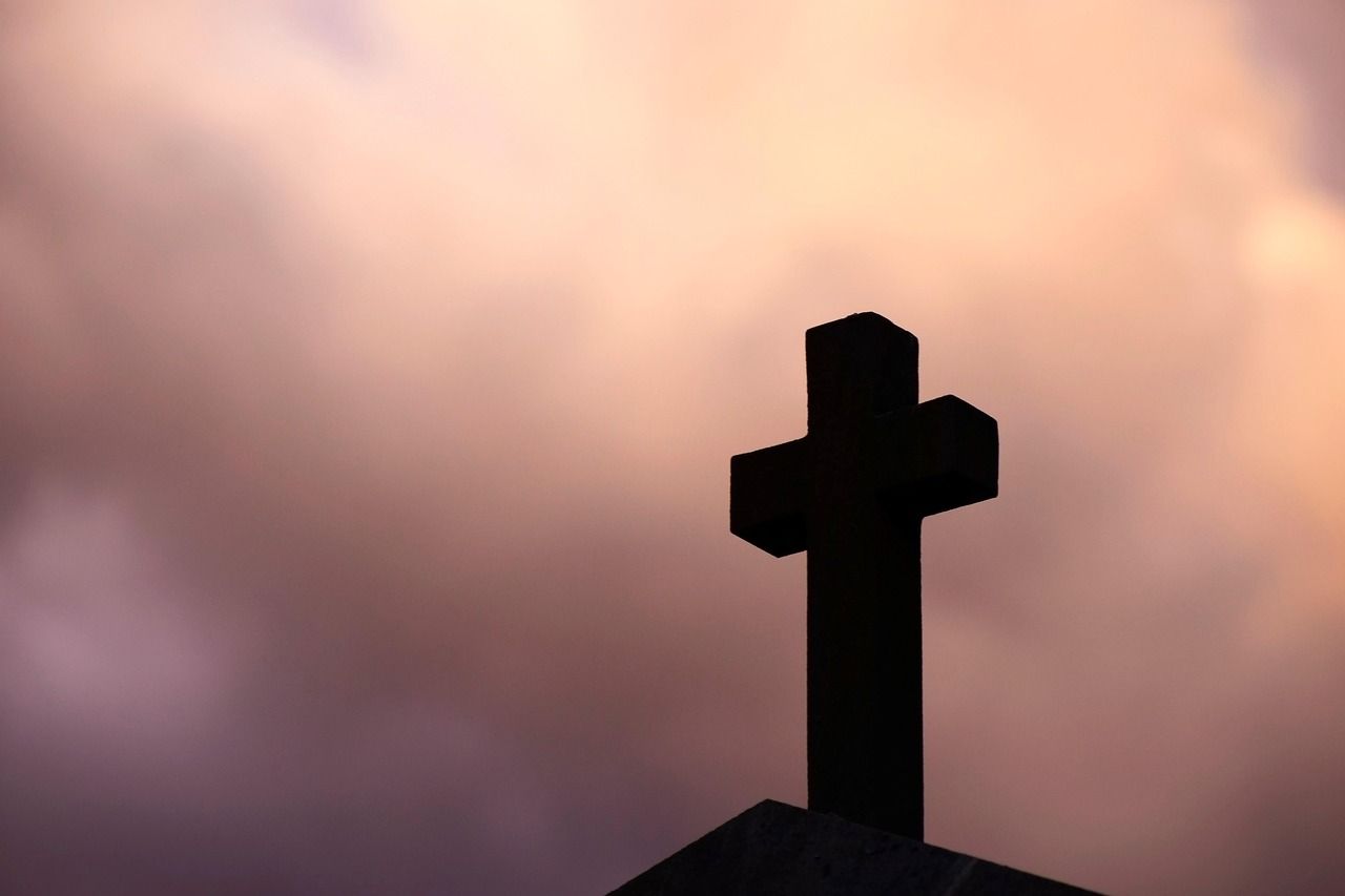 Stone cross silhouetted against the sky in a peaceful cemetery setting