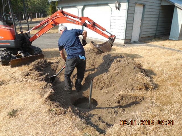 A Man Is Digging a Hole in The Dirt in Front of A House