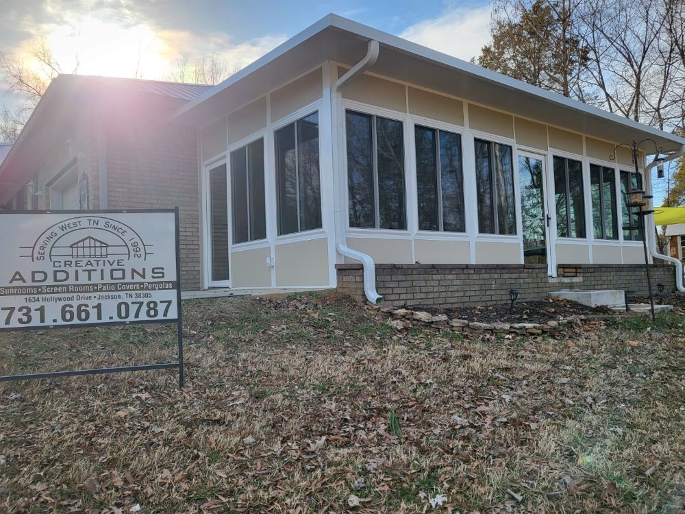 A house with a screened in porch and a sign in front of it