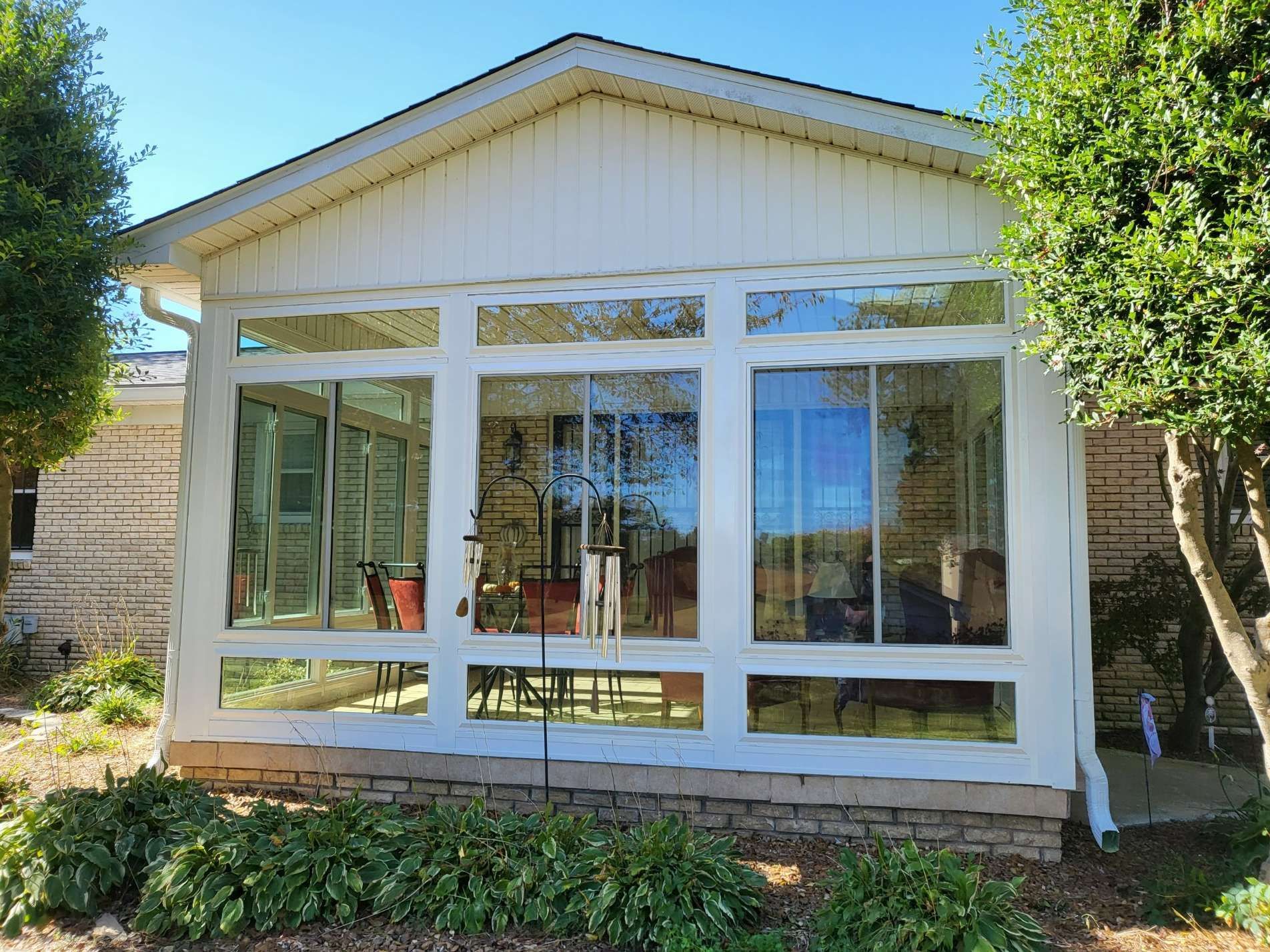 A white house with a sunroom with lots of windows