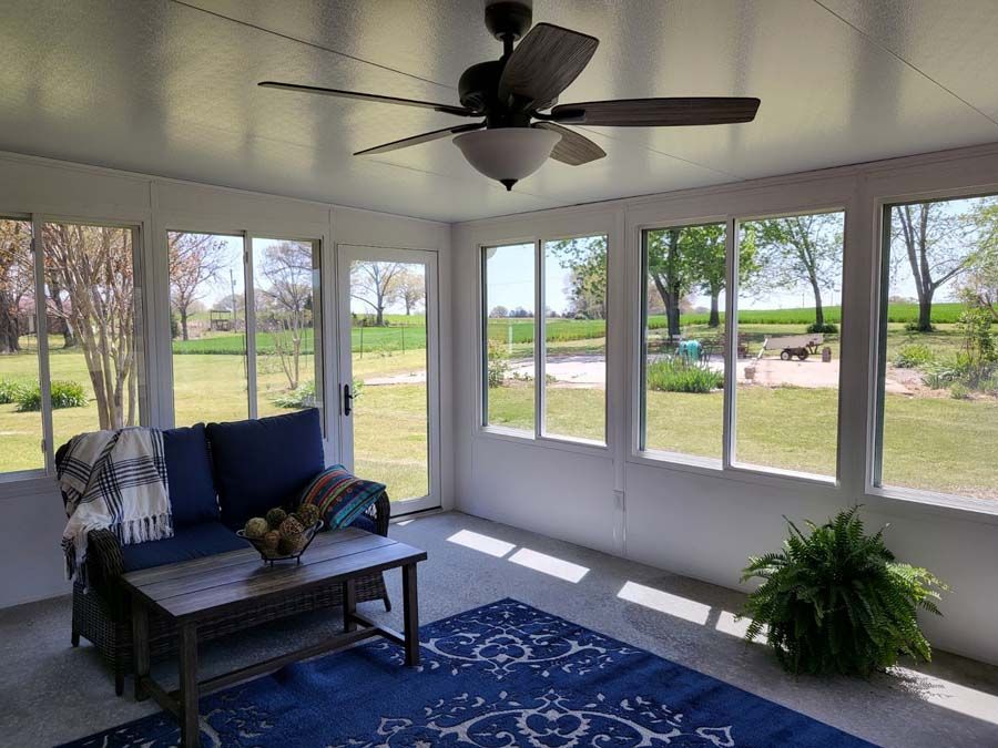 A screened in porch with a ceiling fan and a couch