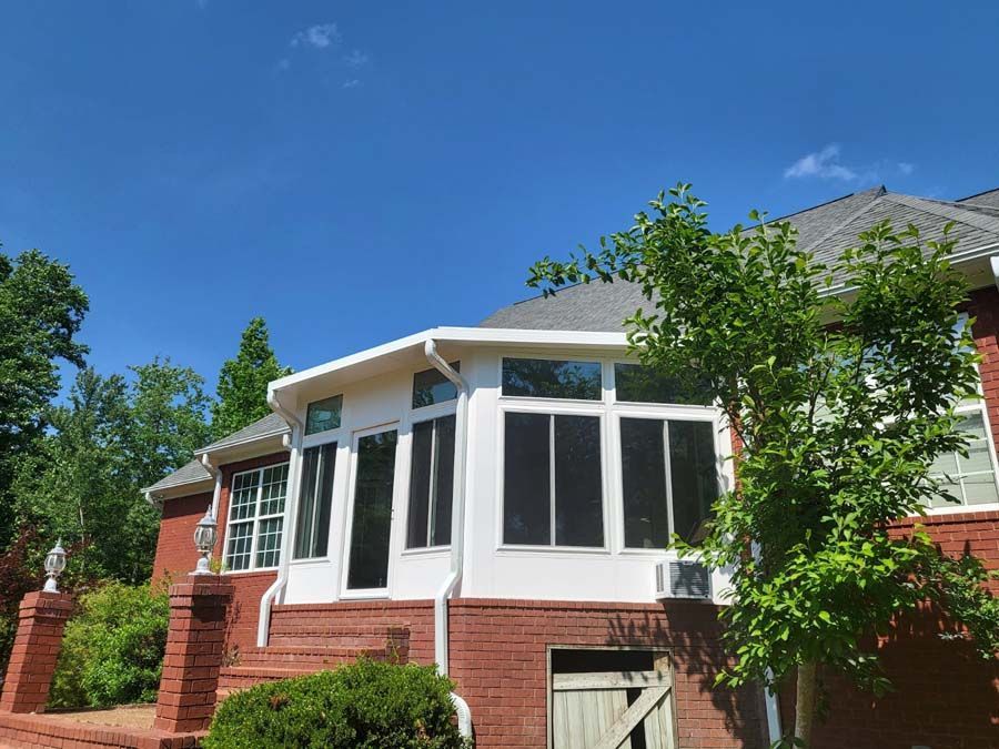A red brick house with a screened in porch and a blue sky in the background