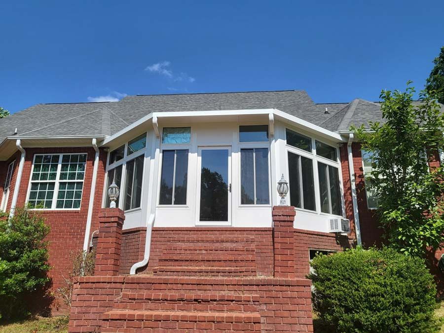 A large brick house with a sunroom and stairs leading up to it
