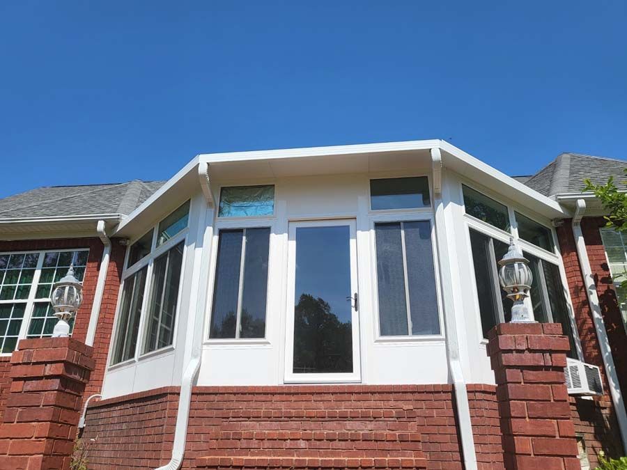 A red brick house with a white sunroom on the side