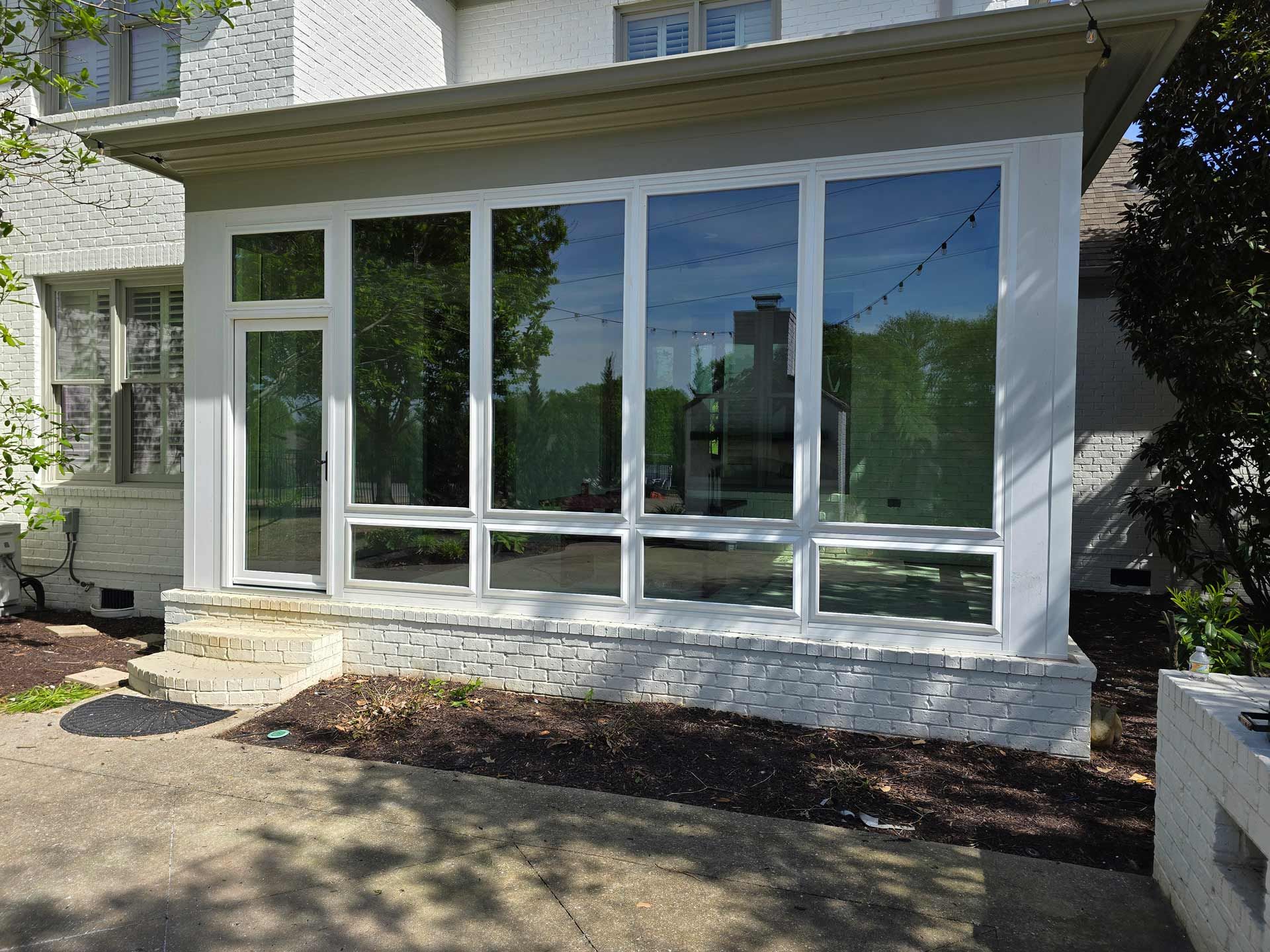 A white house with a sunroom with a lot of windows