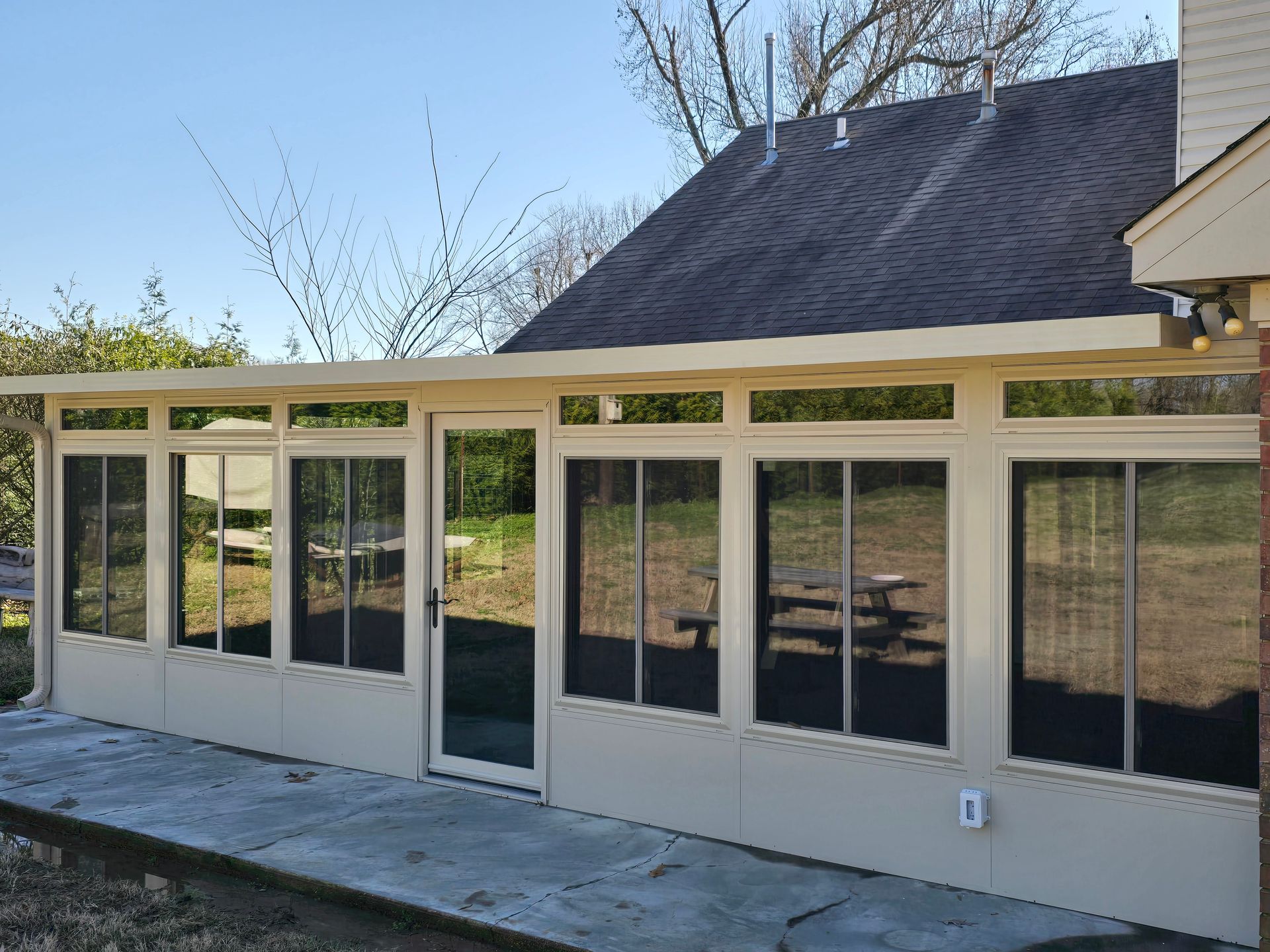 A screened in porch with a picnic table in the backyard of a house