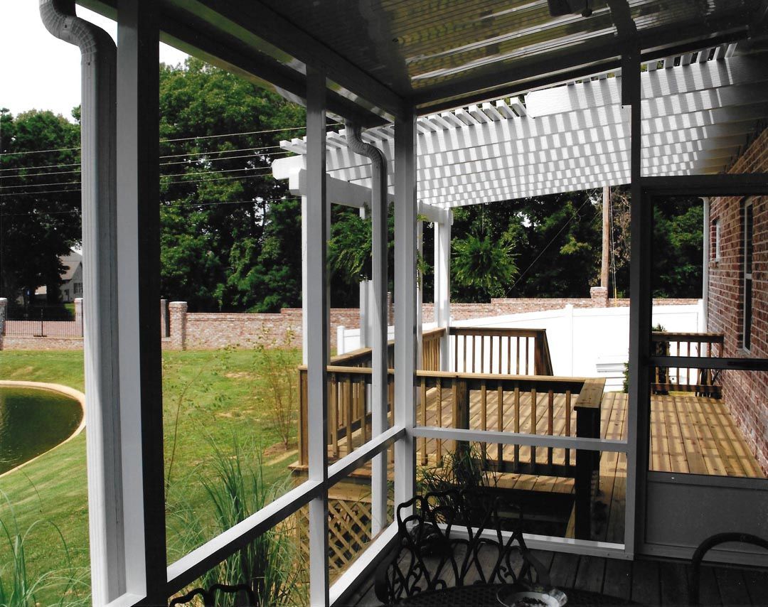 A screened in porch with a deck and a pond in the background