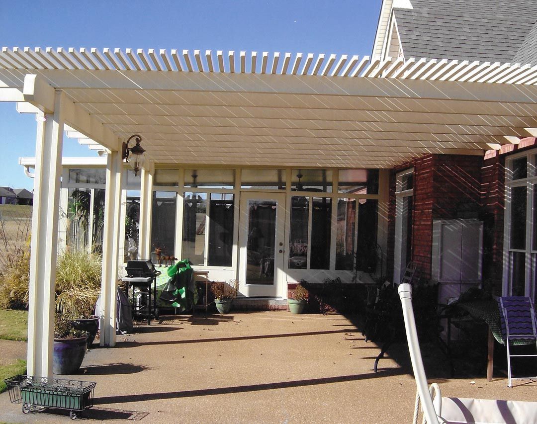 A patio with a white pergola over it