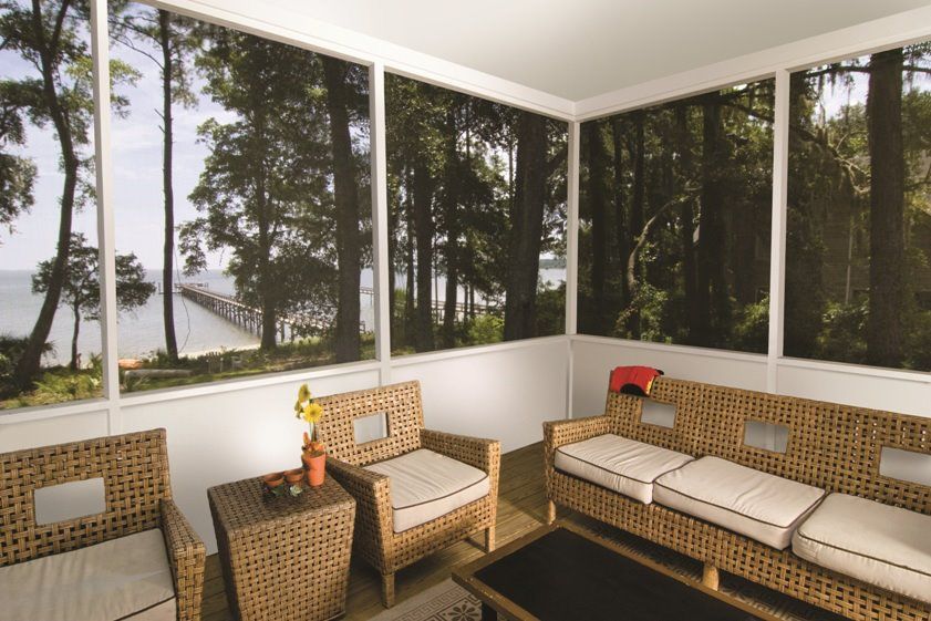 A screened in porch with wicker furniture and a view of the ocean