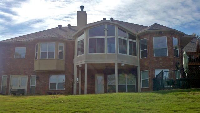 A large brick house with a lot of windows and a large lawn in front of it