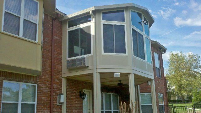A large brick house with a screened in porch and lots of windows