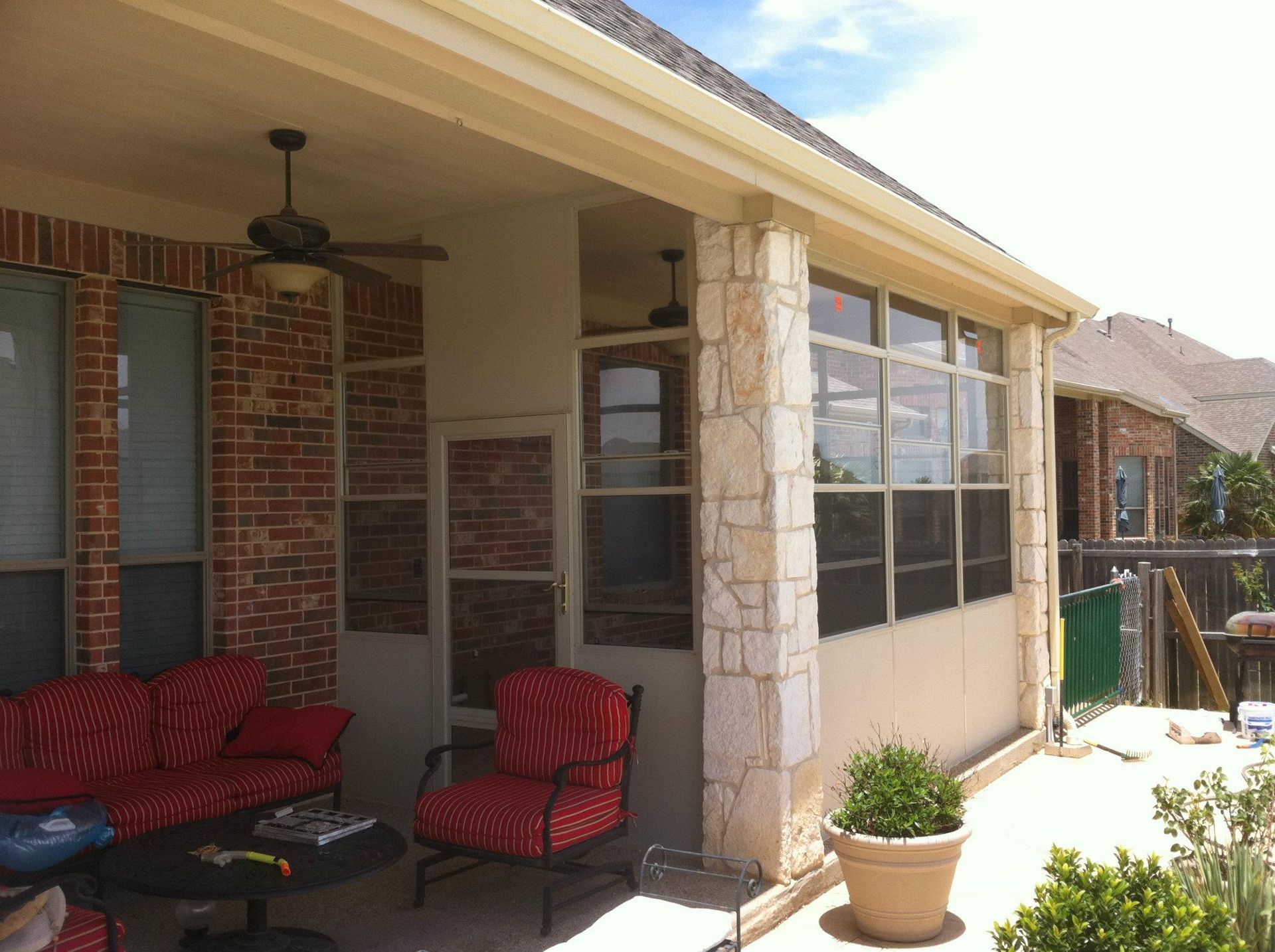A screened in porch with furniture and a ceiling fan