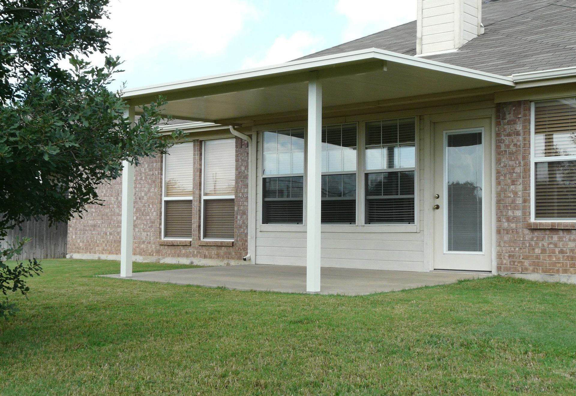 A brick house with a covered patio in front of it
