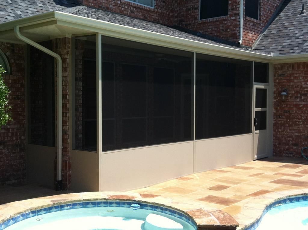 There is a screened in porch next to a swimming pool