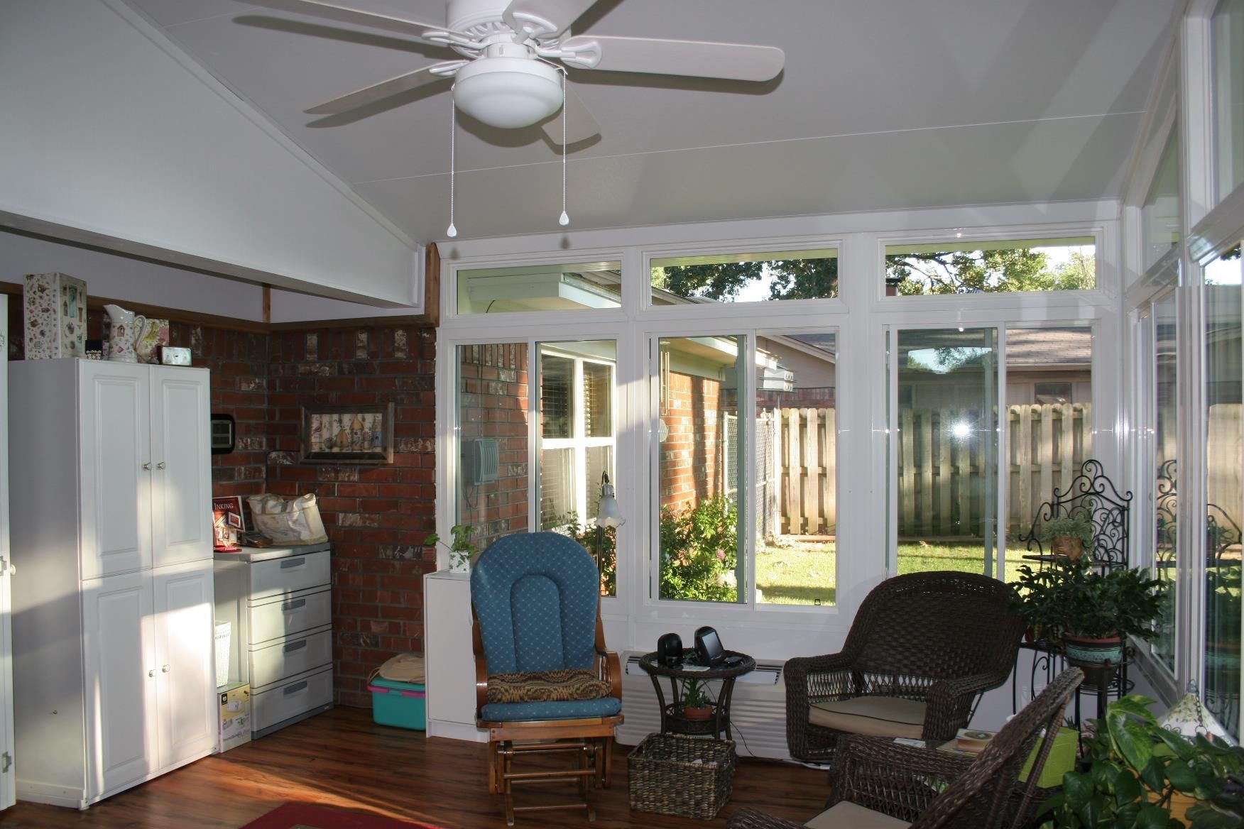 A living room with a ceiling fan and a lot of windows