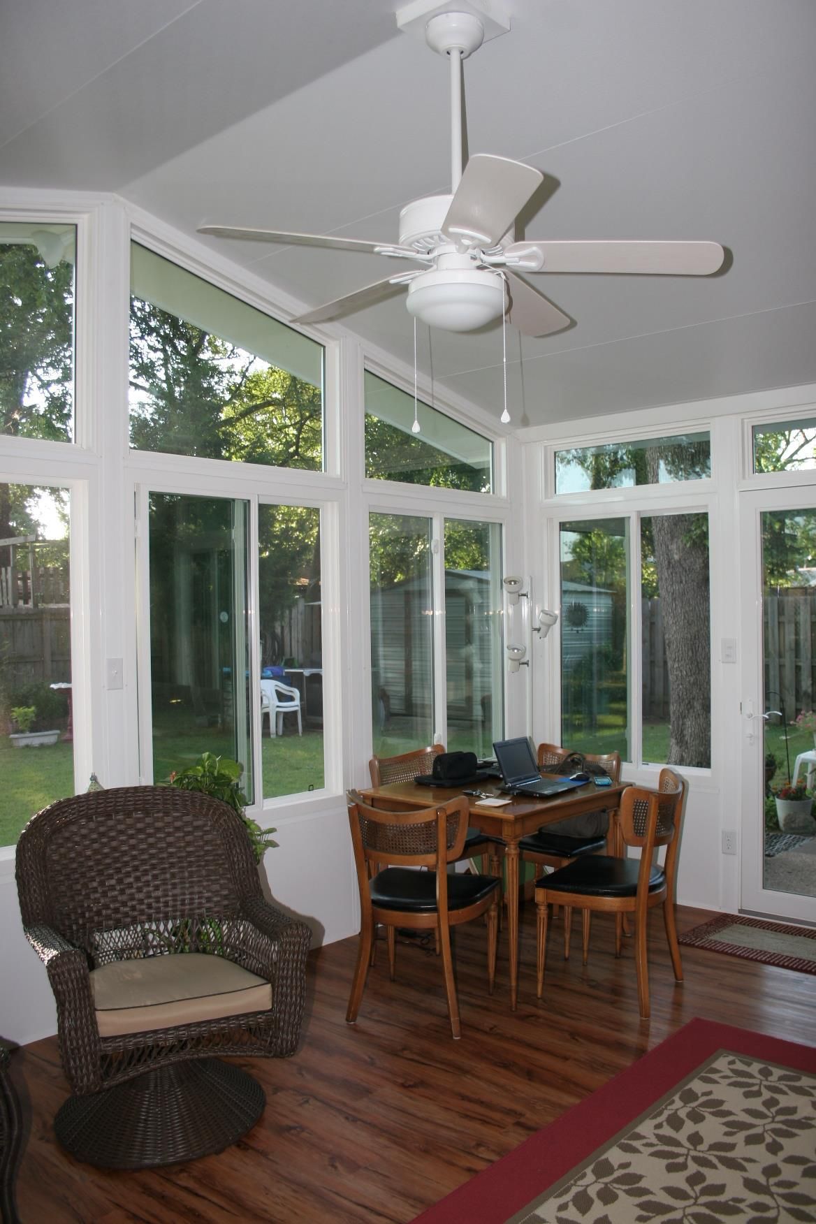 A sunroom with a ceiling fan and a table and chairs