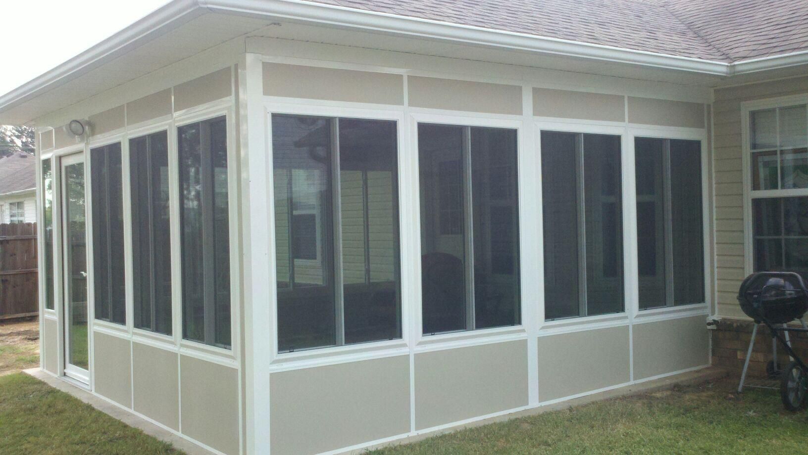 A screened in porch with a grill in the backyard of a house