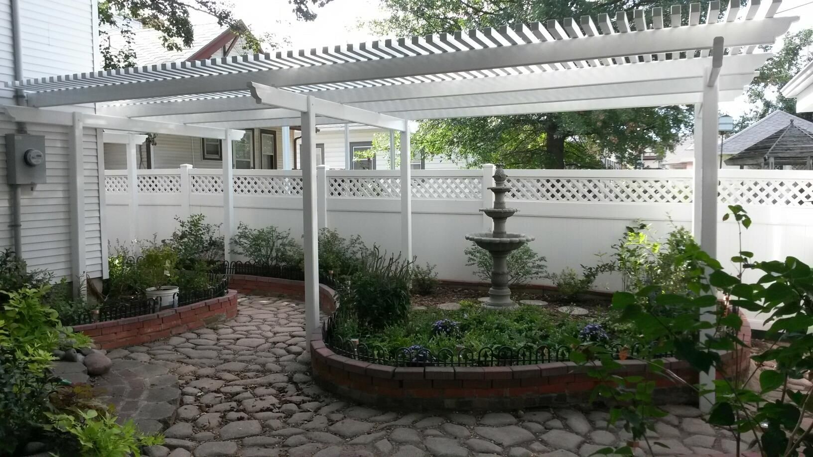 A backyard with a white pergola and a fountain