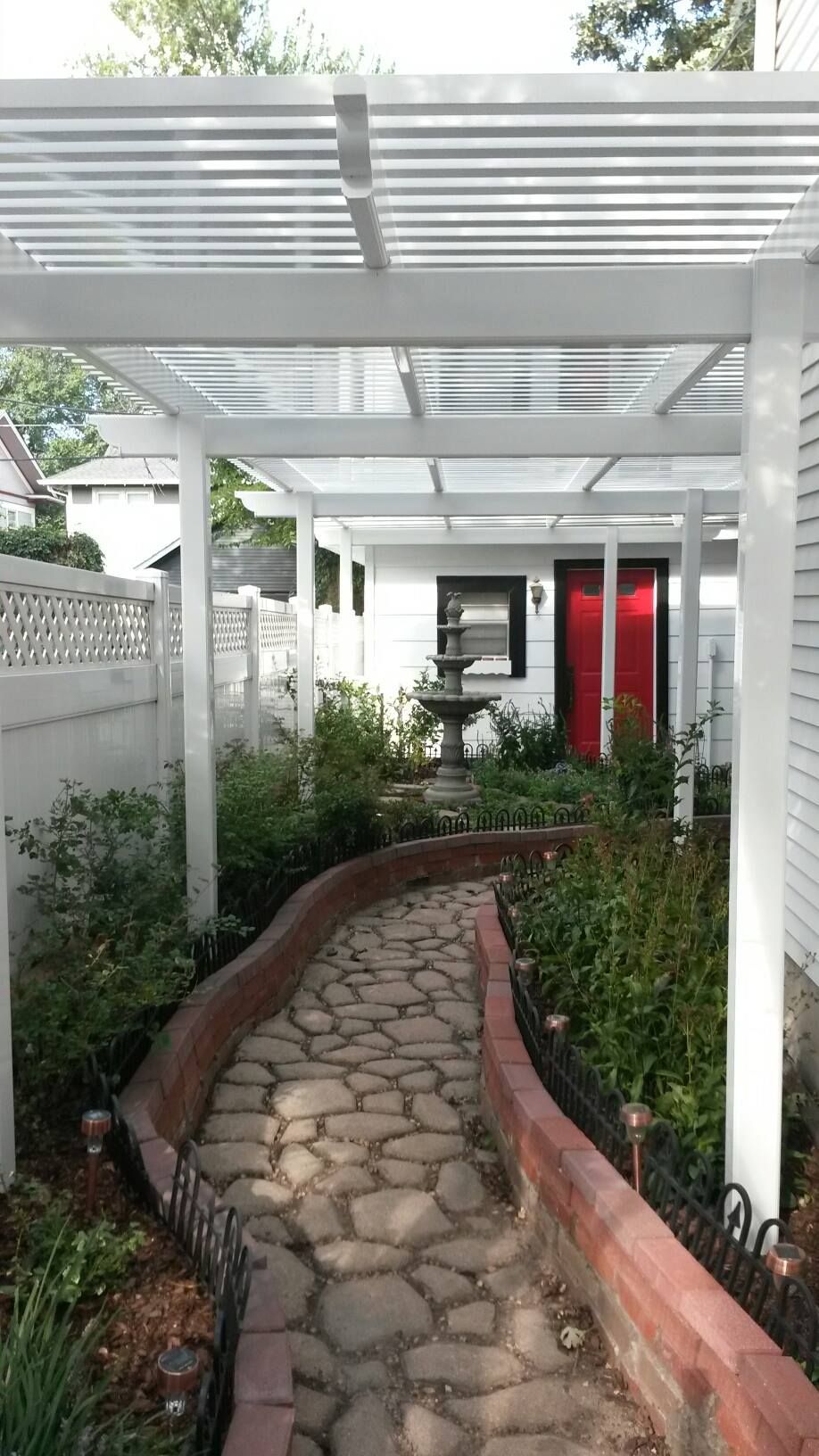 A walkway leading to a house with a pergola over it