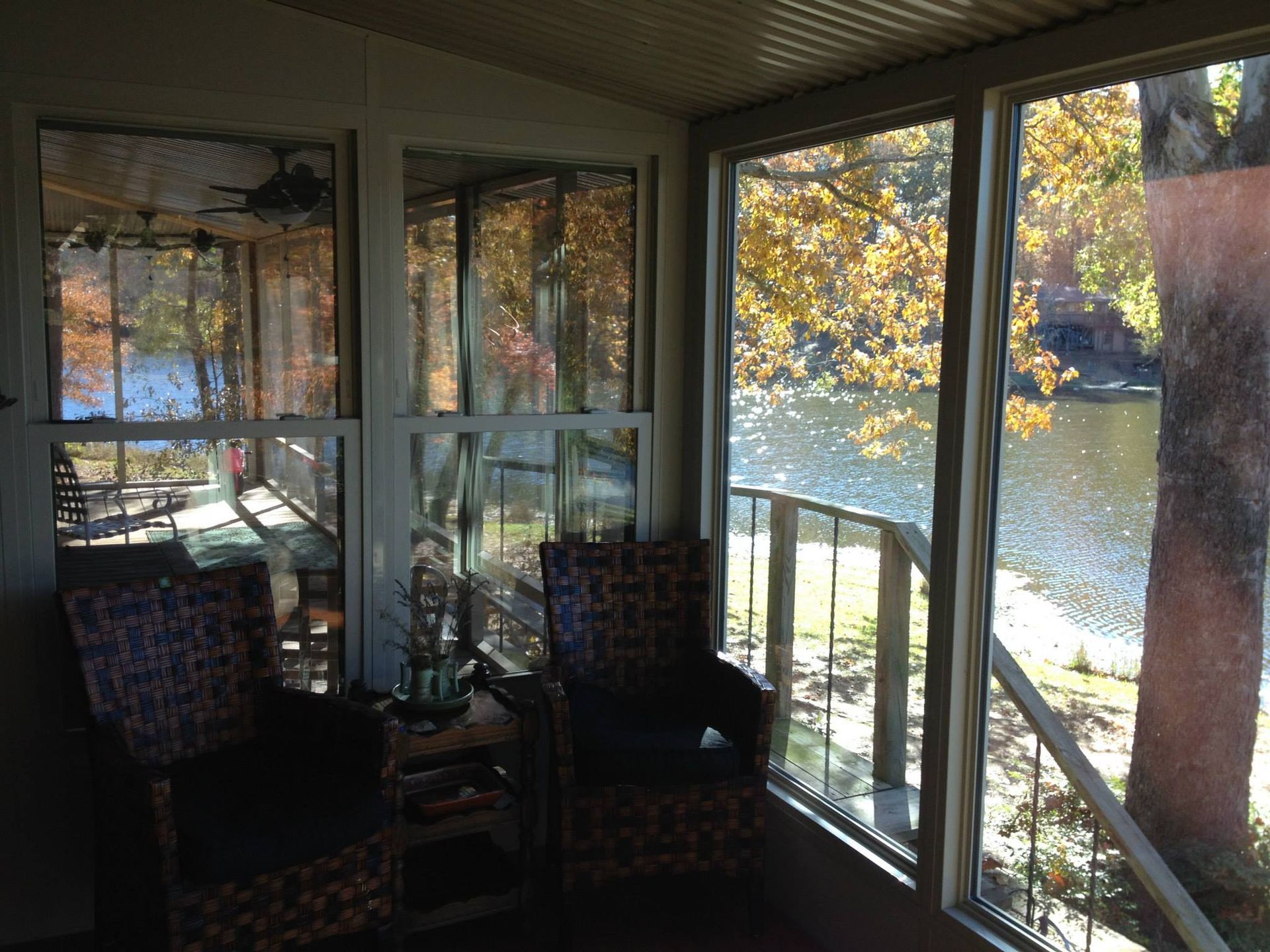 A screened in porch with a view of a lake and trees