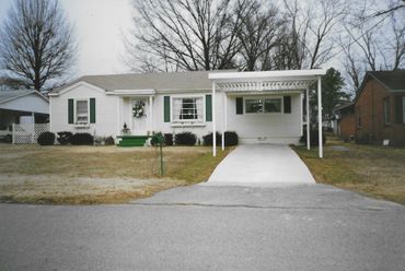 A white house with green shutters and a driveway