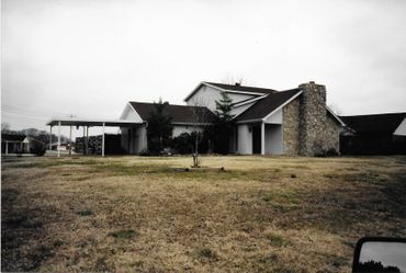 A black and white photo of a large house with a stone chimney