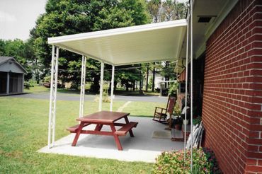 A porch with a picnic table and rocking chairs under a canopy
