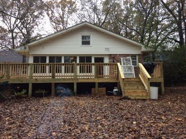 A white house with a large wooden deck in front of it