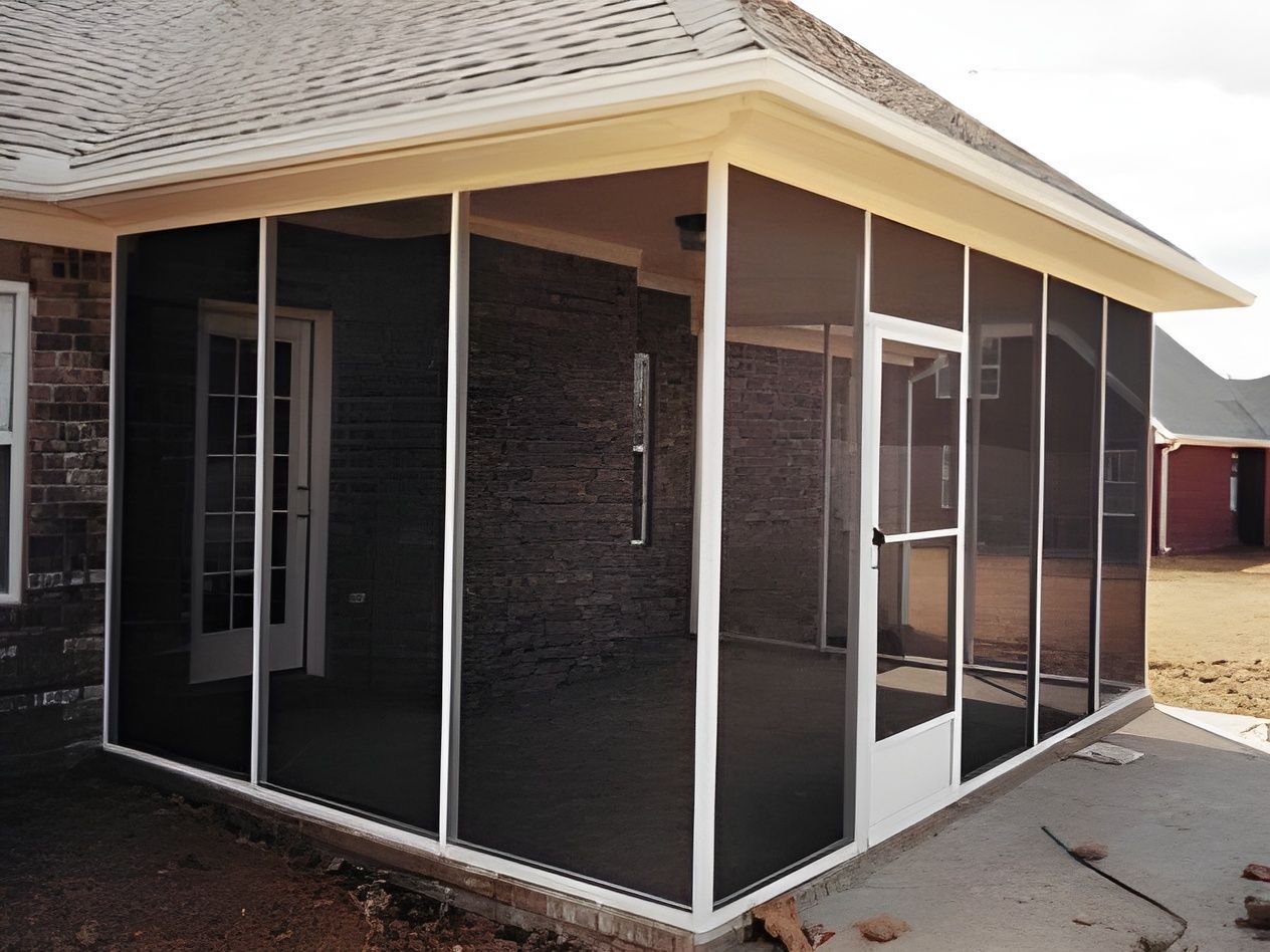 Screened porch with white frame, black screens, and door; adjacent to brick wall. Screened porch with white frame, black screens, and door; adjacent to brick wall.