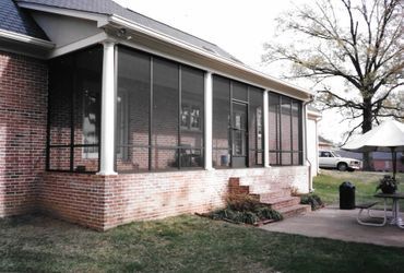 A screened in porch with a picnic table and umbrella