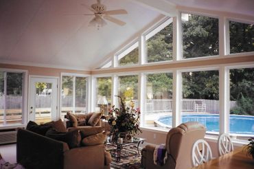 A living room with a lot of windows and a ceiling fan