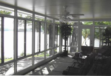 A screened in porch with a lot of windows and a ceiling fan