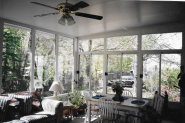 A sunroom with a table and chairs and a ceiling fan