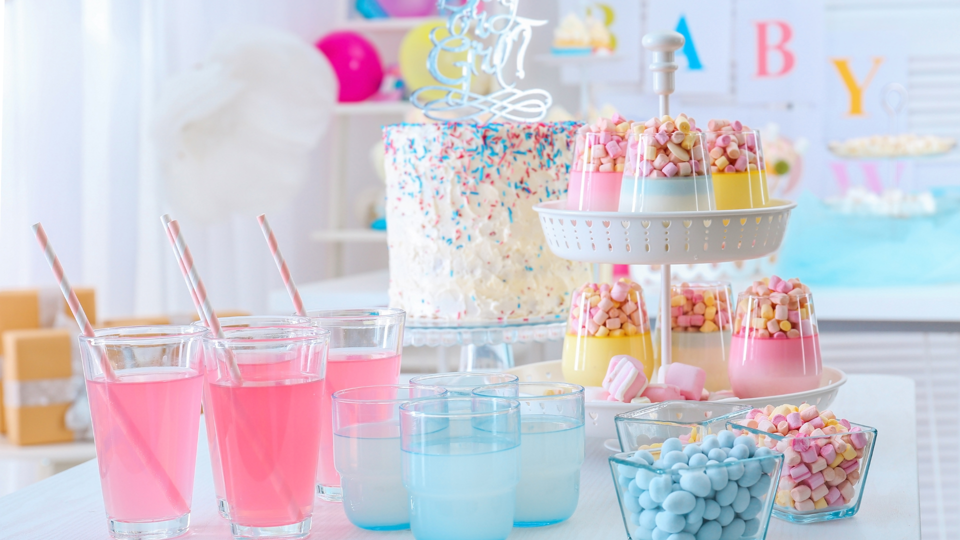 Baby shower dessert table with cake, treats, and colorful drinks.