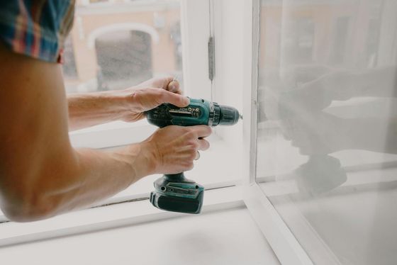 A man is using a drill to install a window.